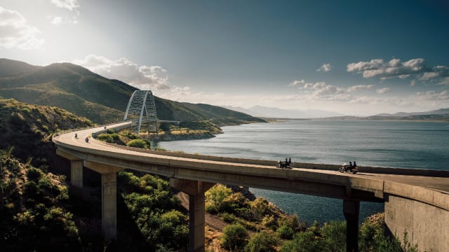 Motorcyclists driving over bridge in California with water in background