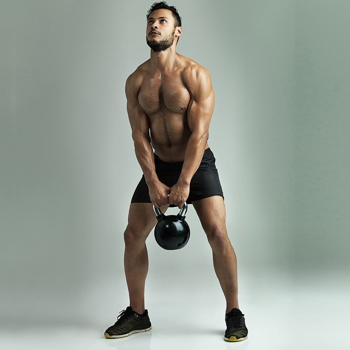 Muscular shirtless man workout with kettlebells in L Sit position