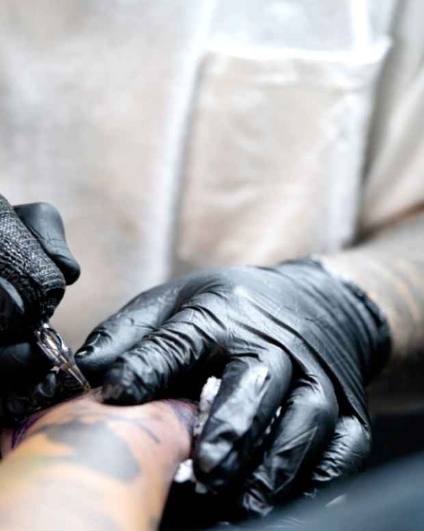 Stock photo of a tattoo artist working on a man's arm.