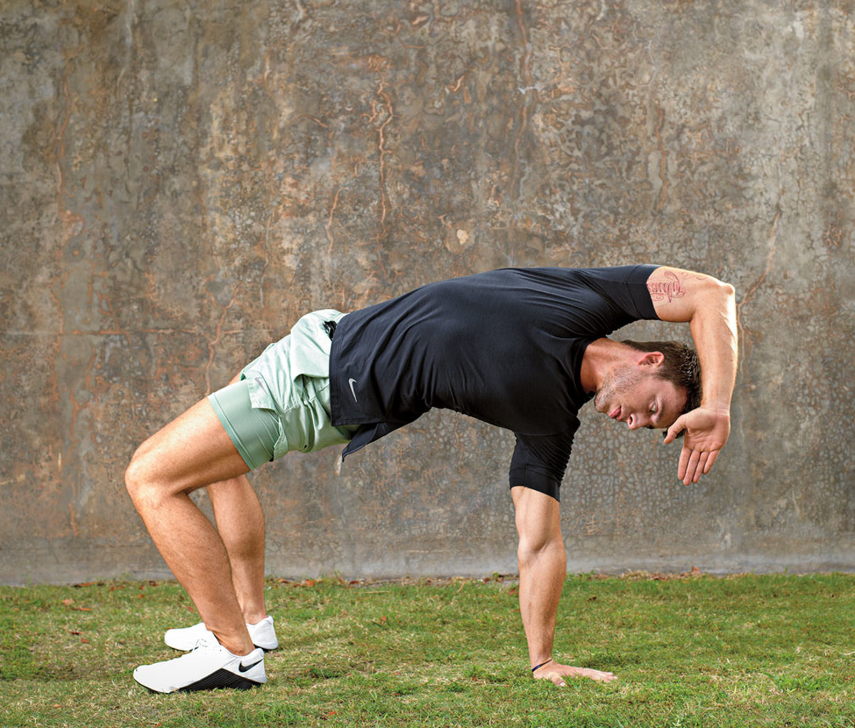 Caucasian man demonstrating thoracic bridge exercise outdoors  on grass