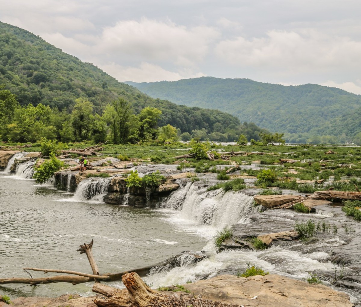 Man and son standing near river runoff and mini falls