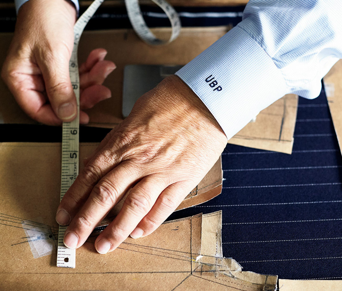 Close-up of tailor's hands taking measurements for suit