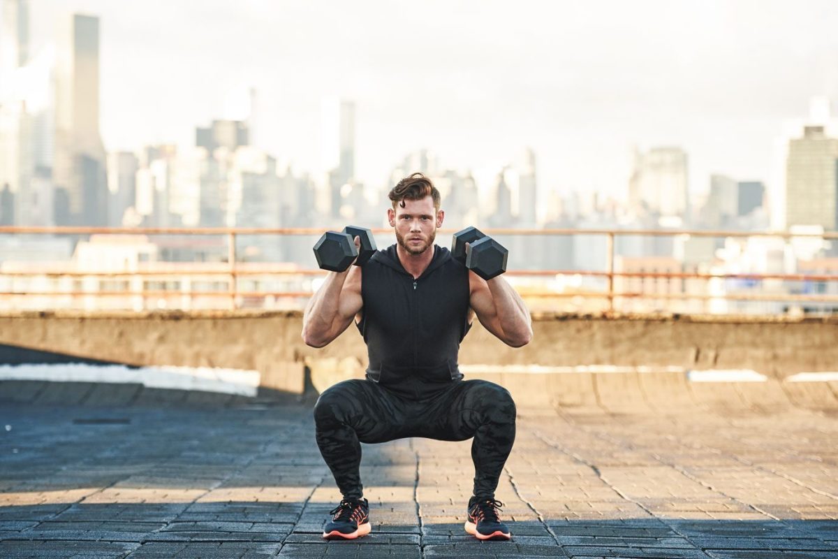 Man doing dumbbell squat on rooftop