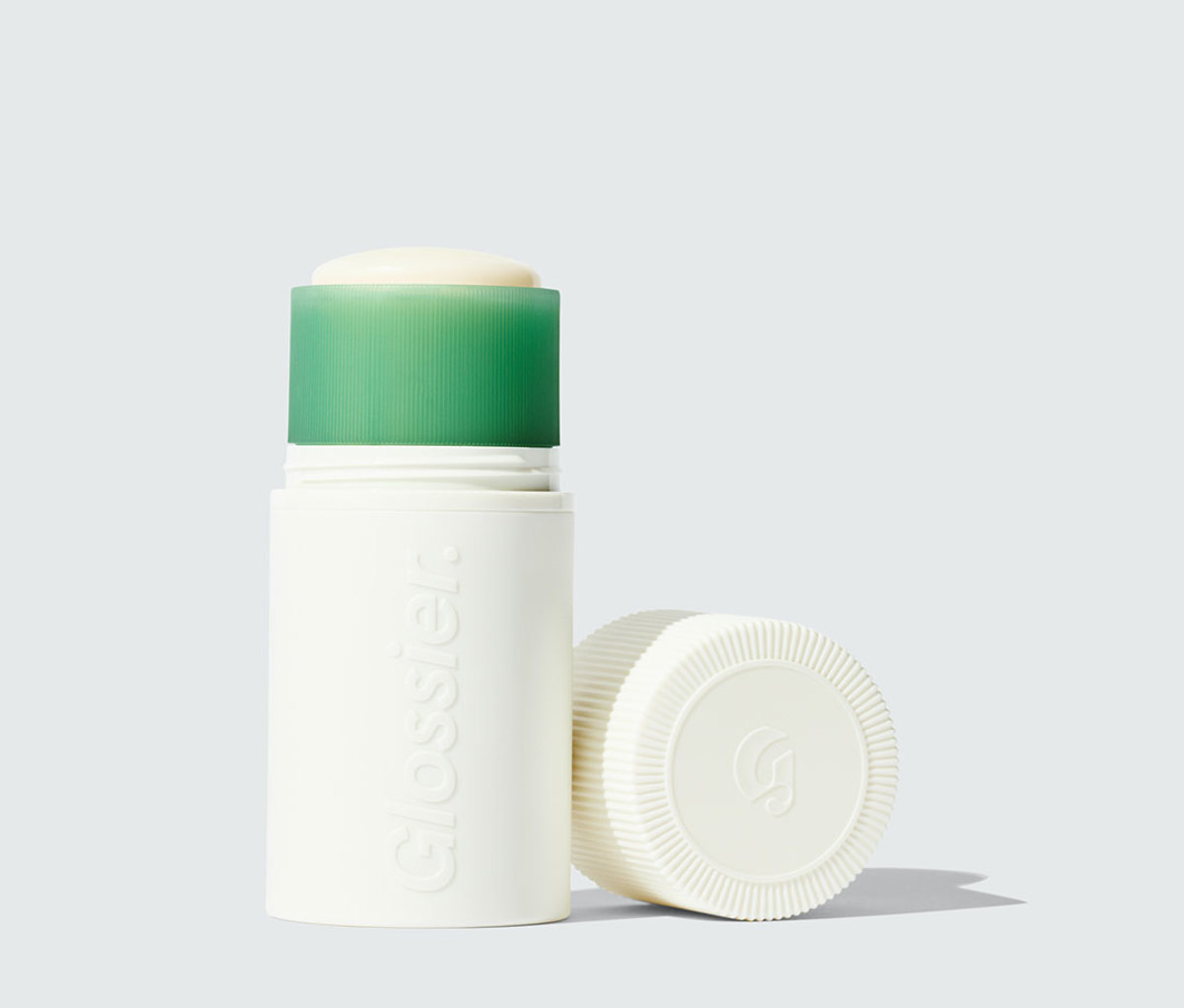 White container of deodorant with green top