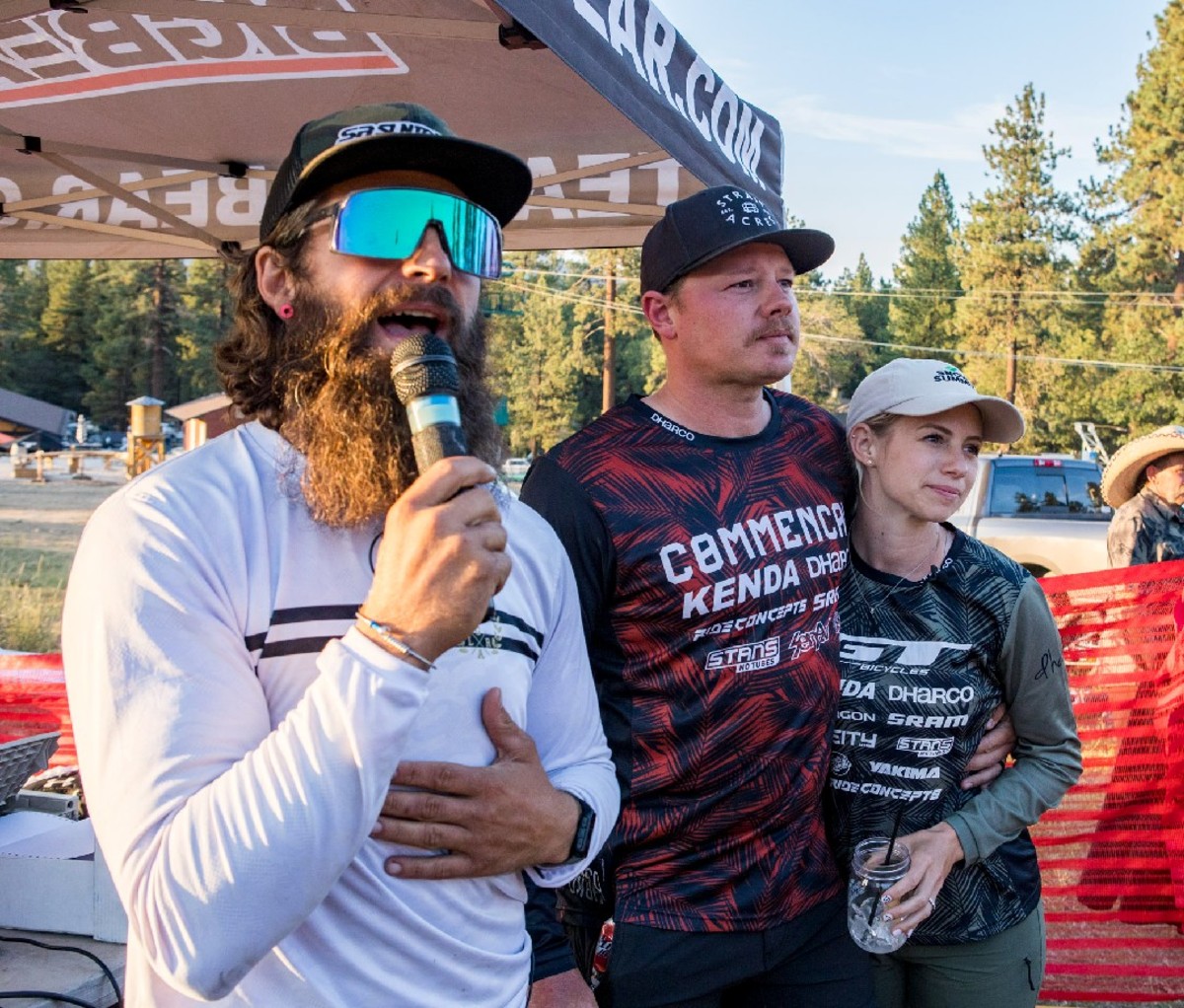 An announcer stands next to Kyle and Rachel Strait, the organizers of the event.