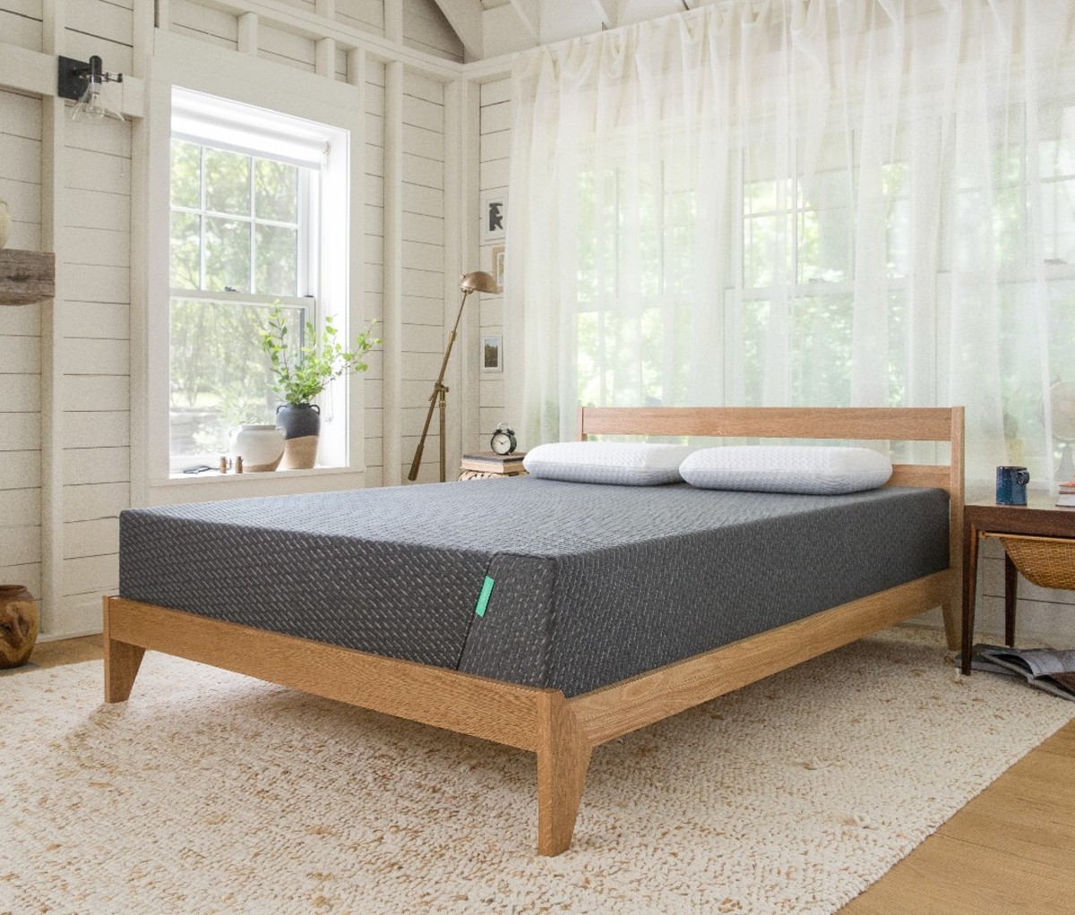 A Tuft & Needle Mint Mattress on a bed frame in a brightly-lit room.