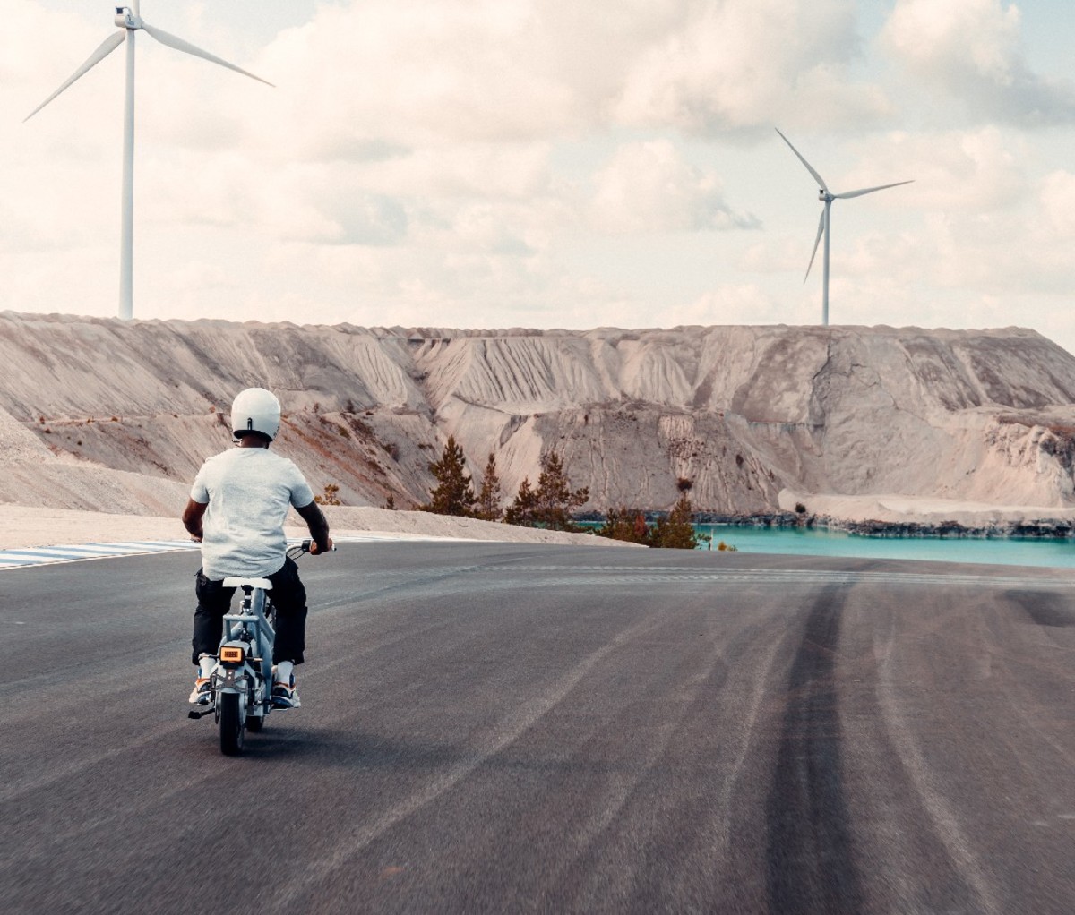 Man riding motorbike with wind turbines in distance