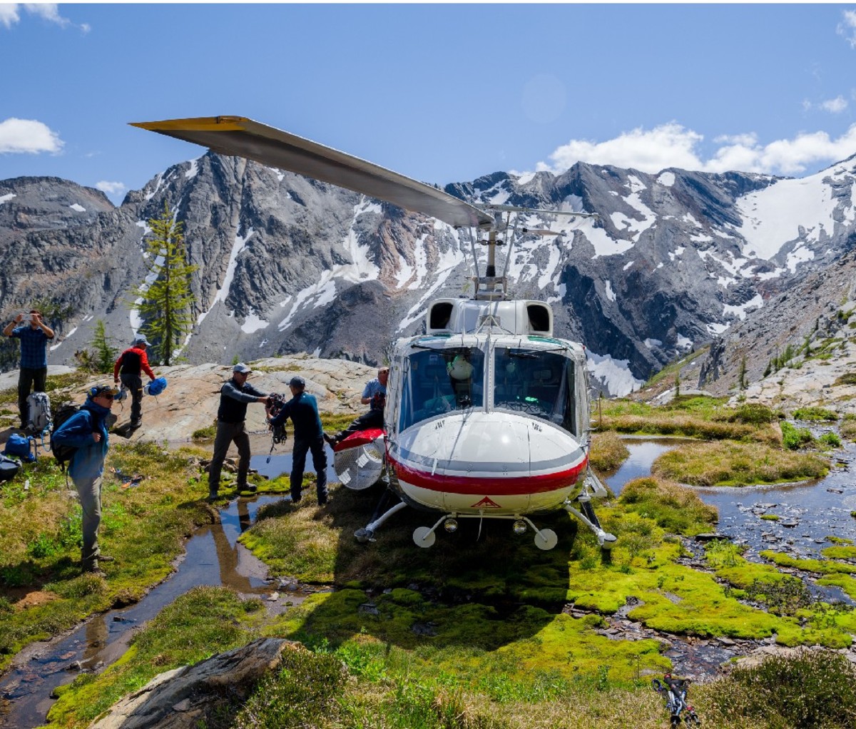 Hikers disembark from a helicopter parked in the Western Canadian mountains