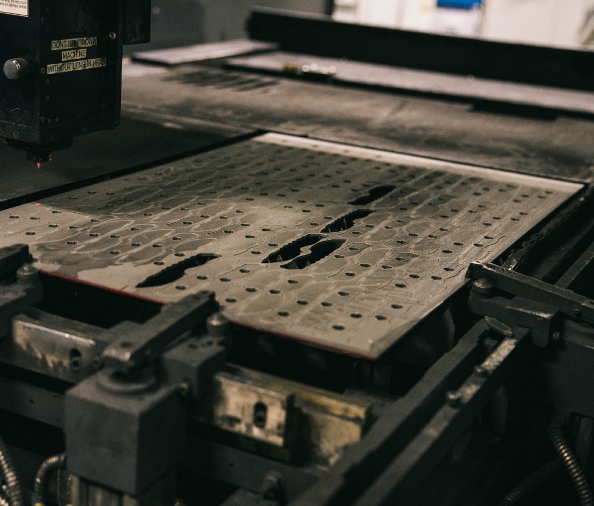 A large steel sheet with blade cutouts lays flat on a machine