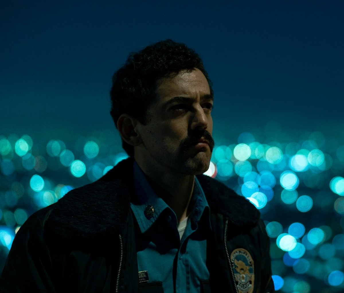 Closeup of Narcos: Mexico actor Luis Gerardo Méndez at night with the lights of Juarez, Mexico in the background