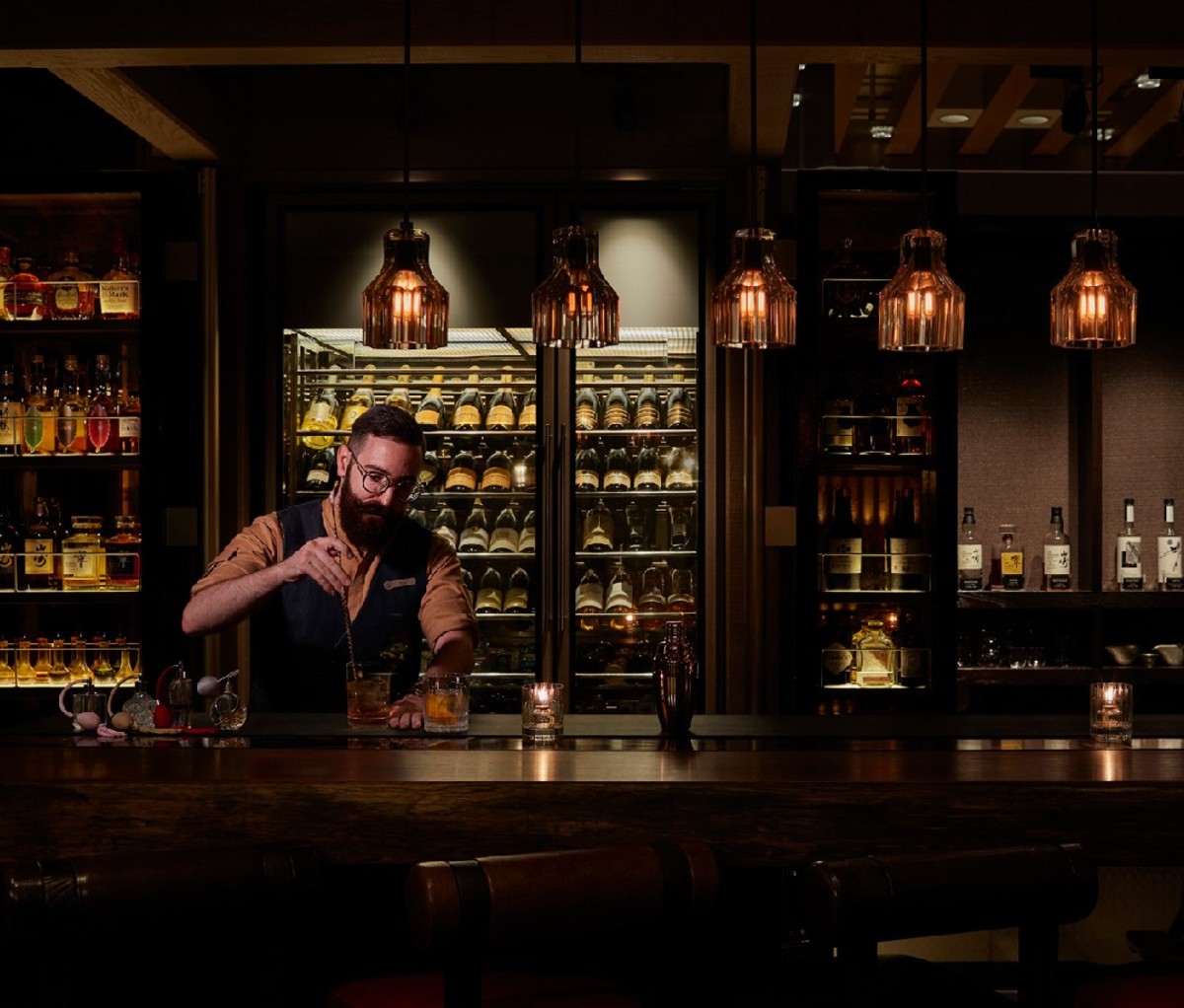 Bartender in dimly lit bar making cocktail