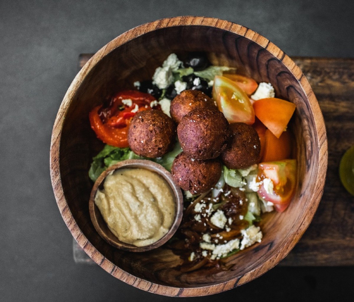 Bowl with greens, falafel, tomato. and tahini