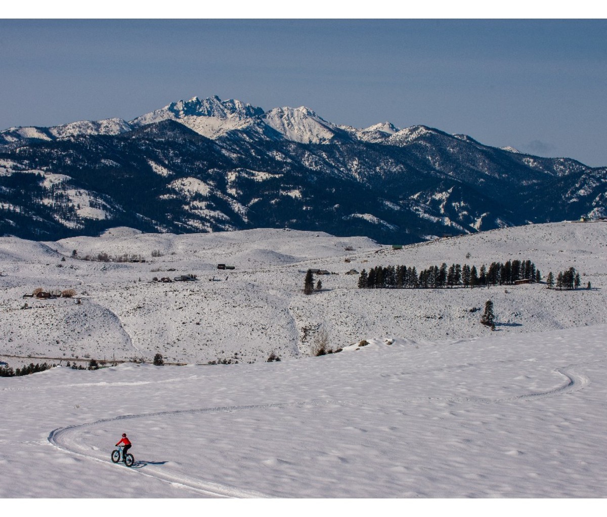 Long shot of a mountain biker riding along a snowy fat bike trail in northern Washington's Methow Valley