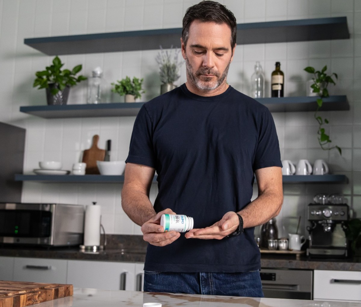 Caucasian man in kitchen taking gummies