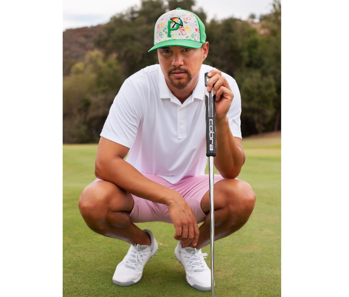 Male golfer kneeling on the green in golf attire