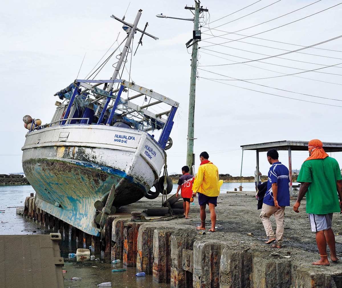 A spared vessel sits in a wreckage-clogged wharf.