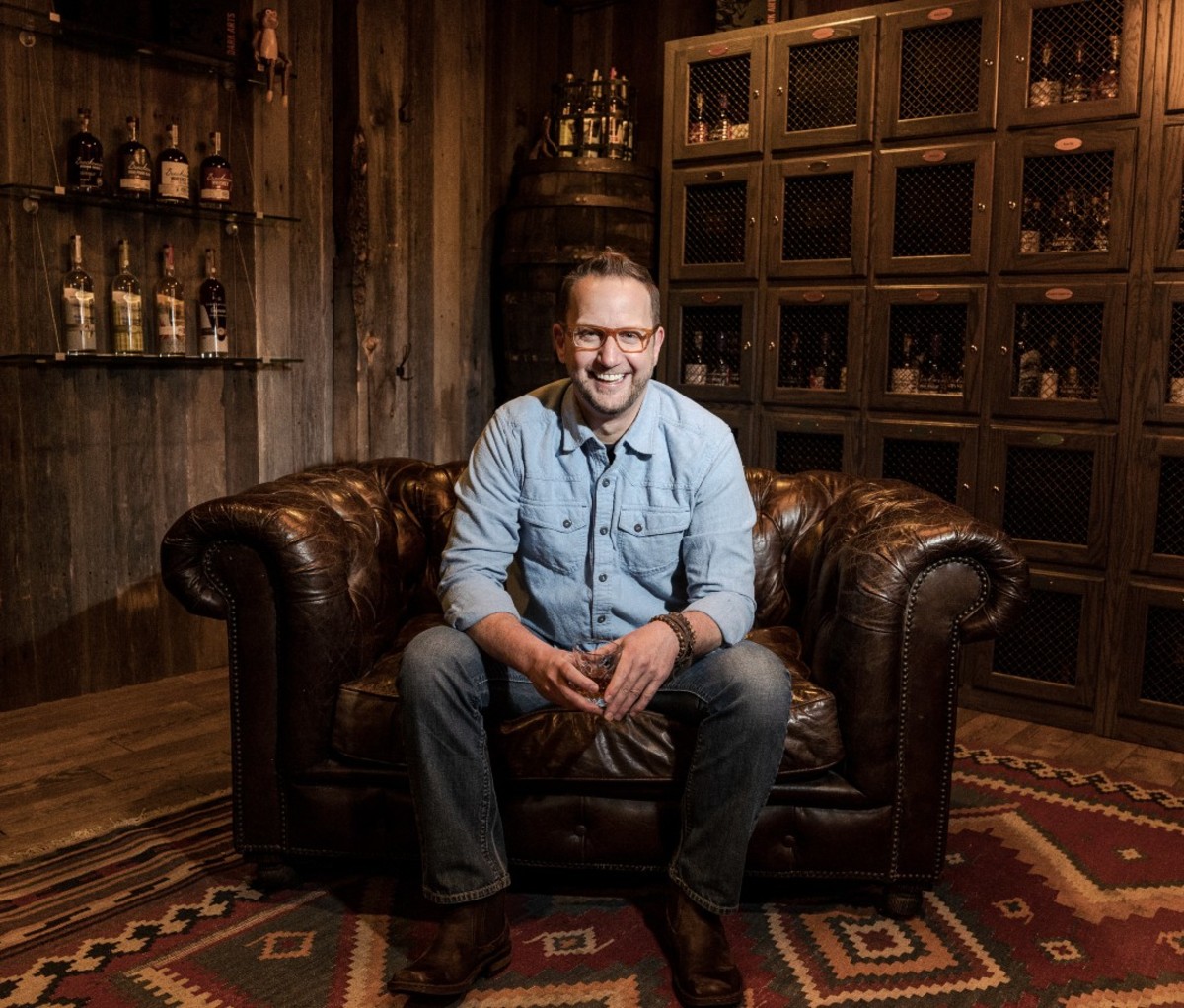 Portrait of caucasian male wearing glasses and blue button-down shirt sitting in leather chair