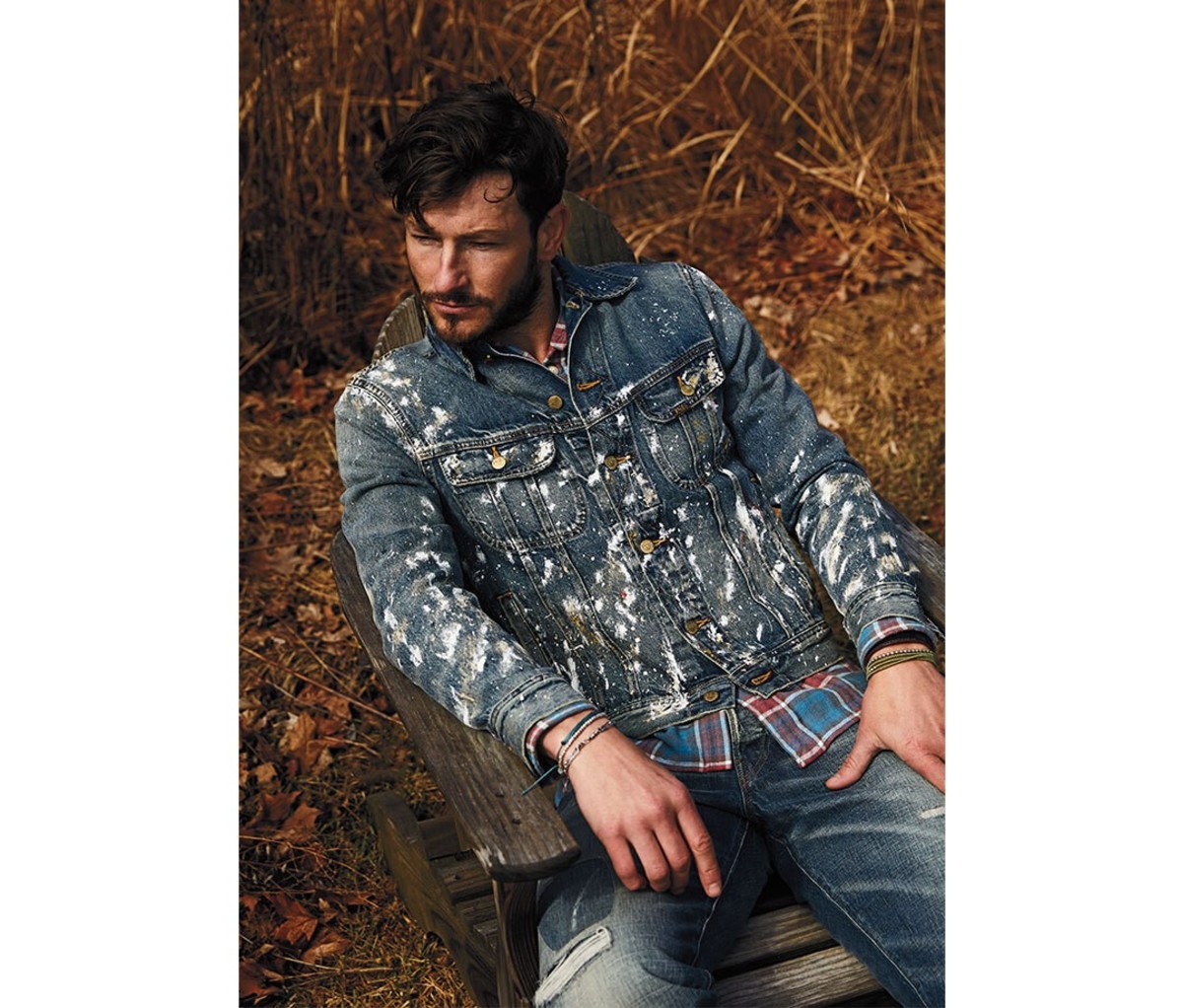 A man in a jean jacket sitting in the woods