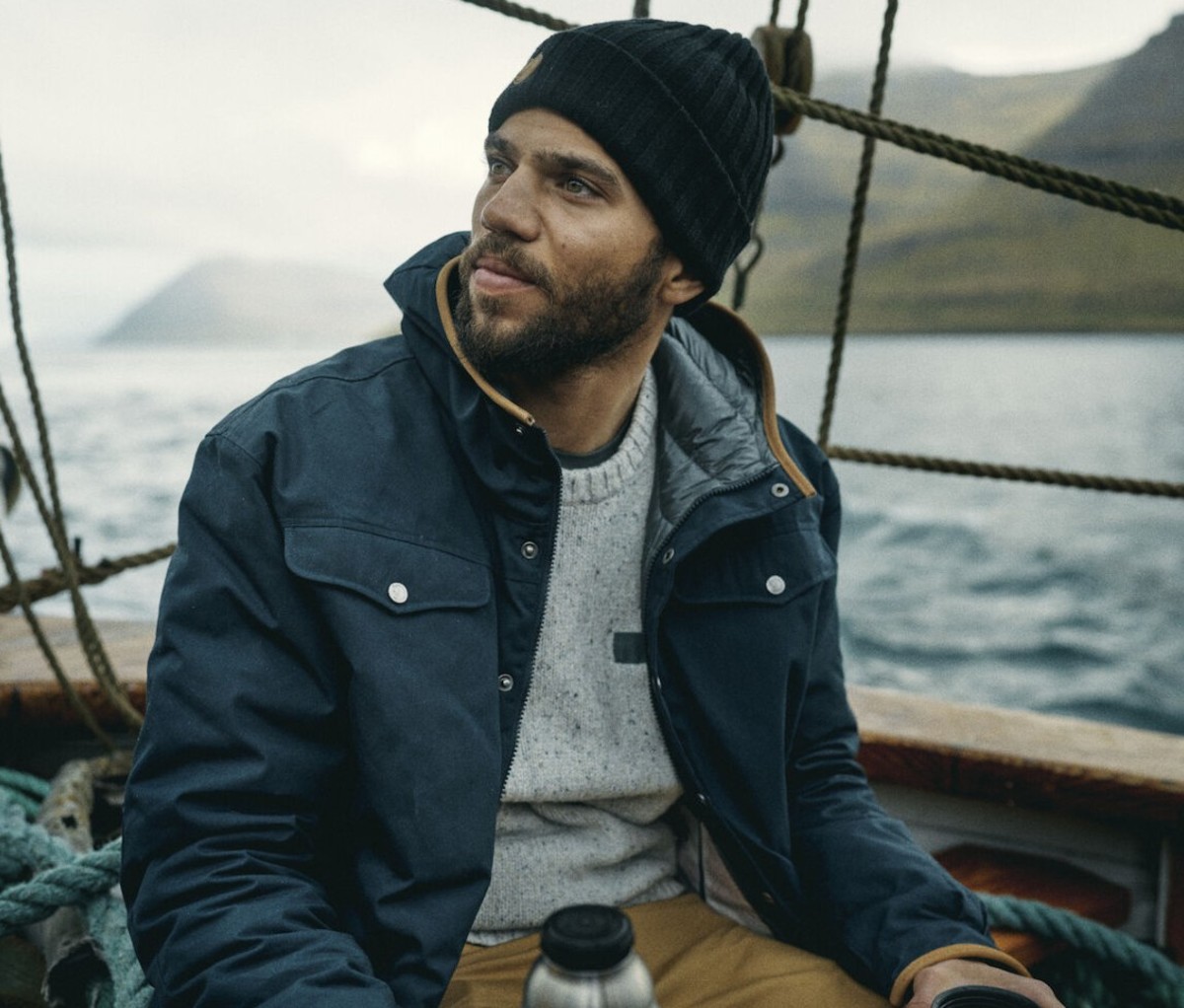 Man wearing blue waxed jacket and beanie on boat