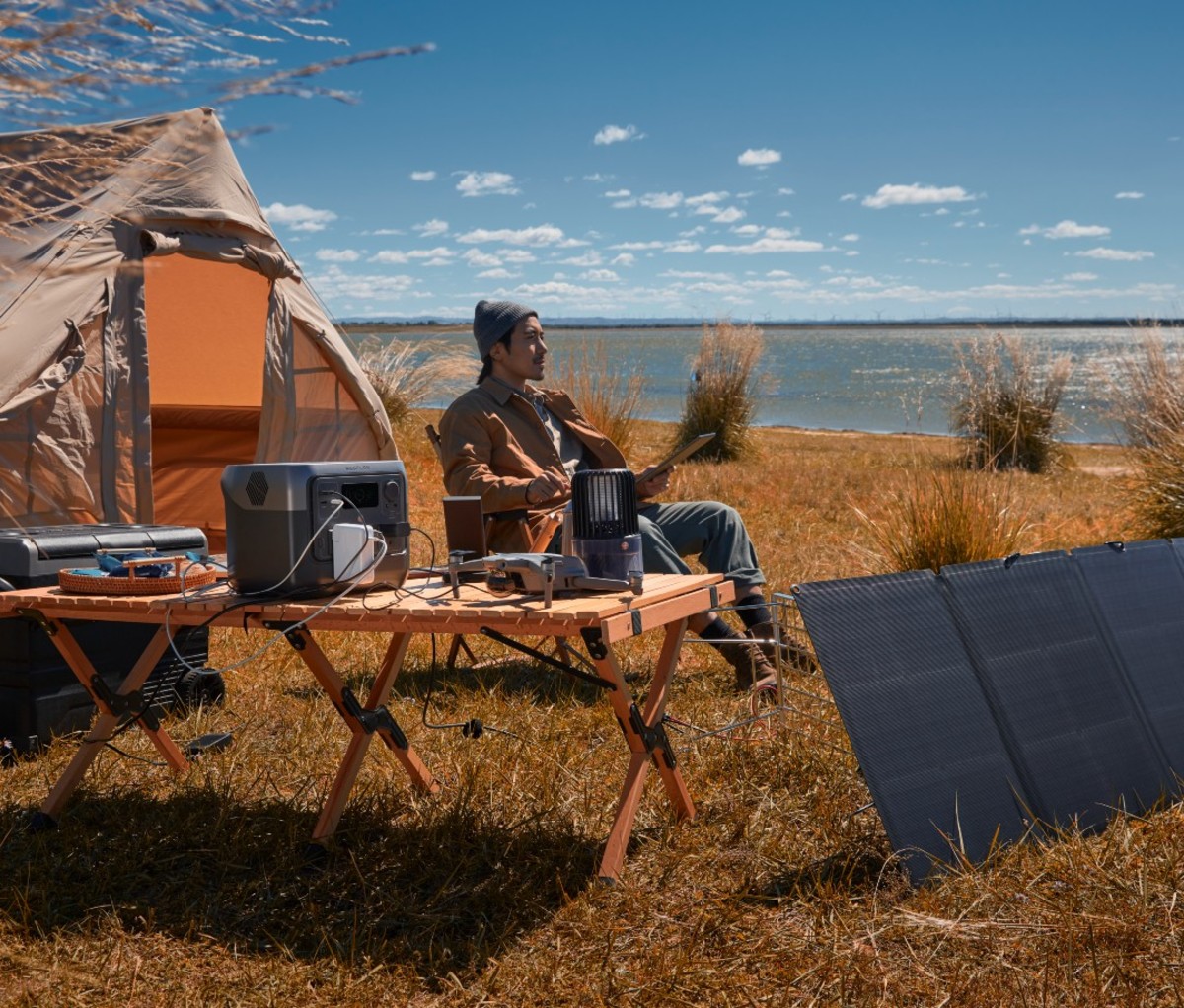 Man of Asian descent sitting outdoors with camp setup