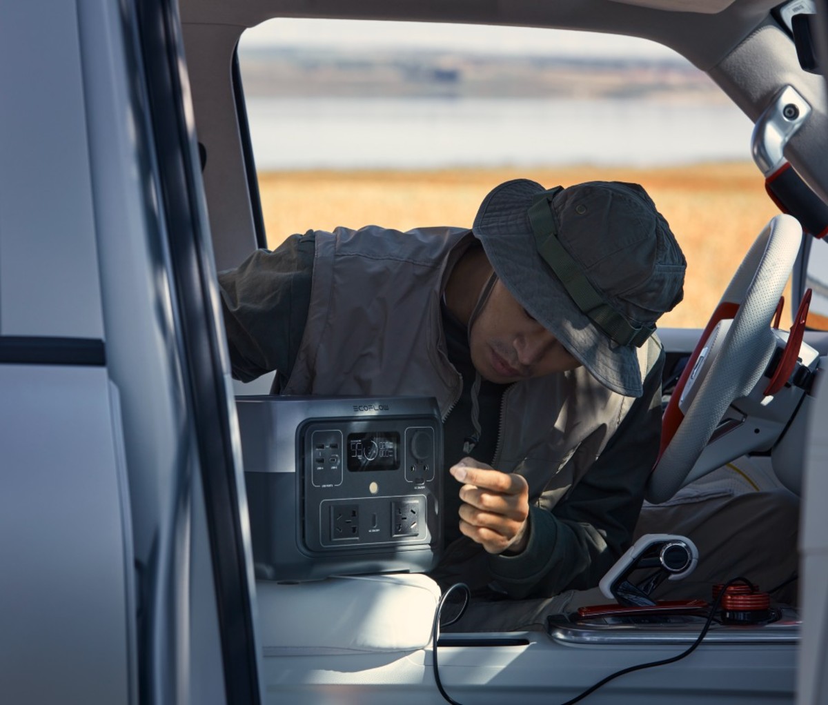 Man of Asian descent plugging in portable charger to car