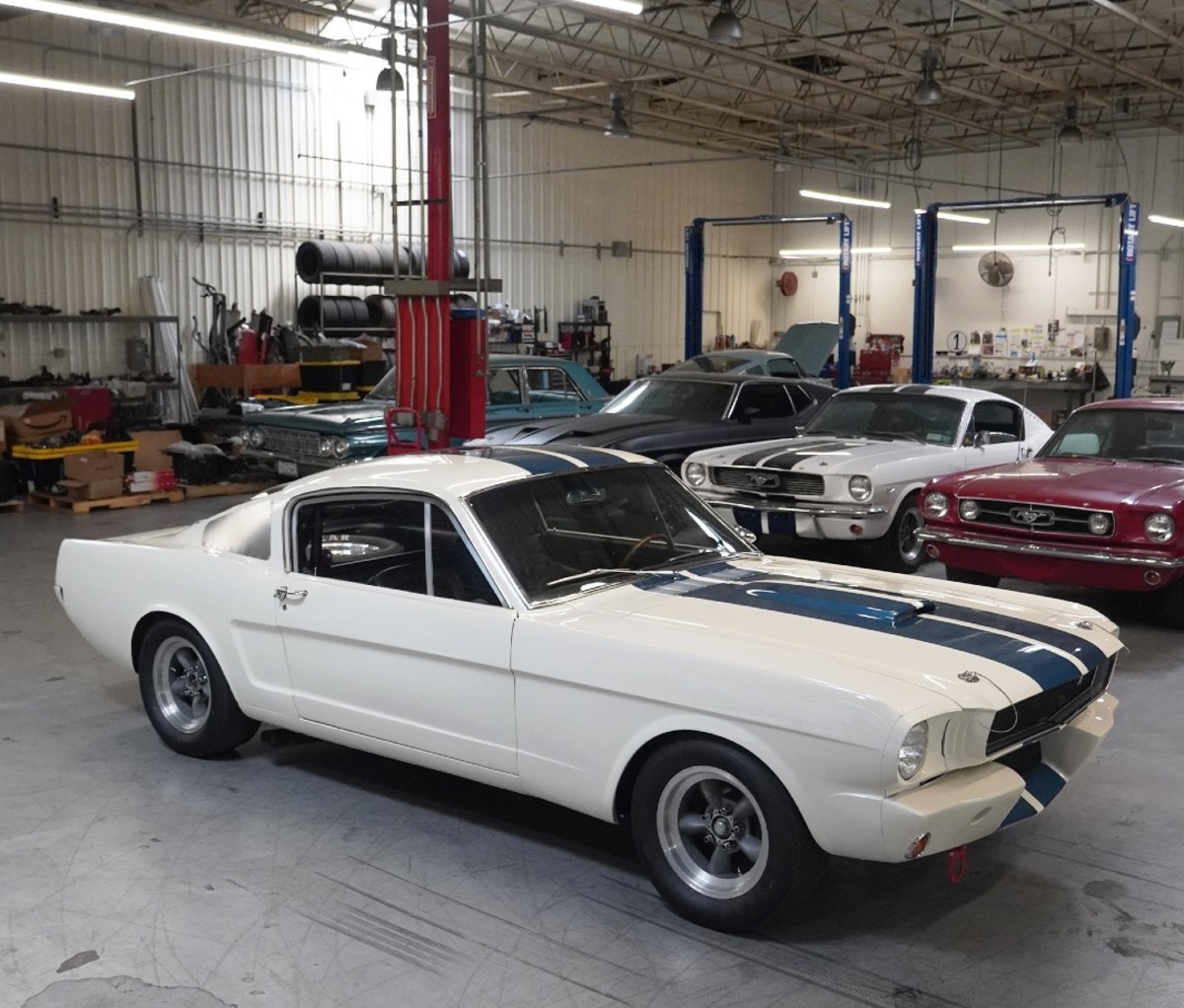 Garage with a white vintage Ford Mustang and other Mustangs behind it.