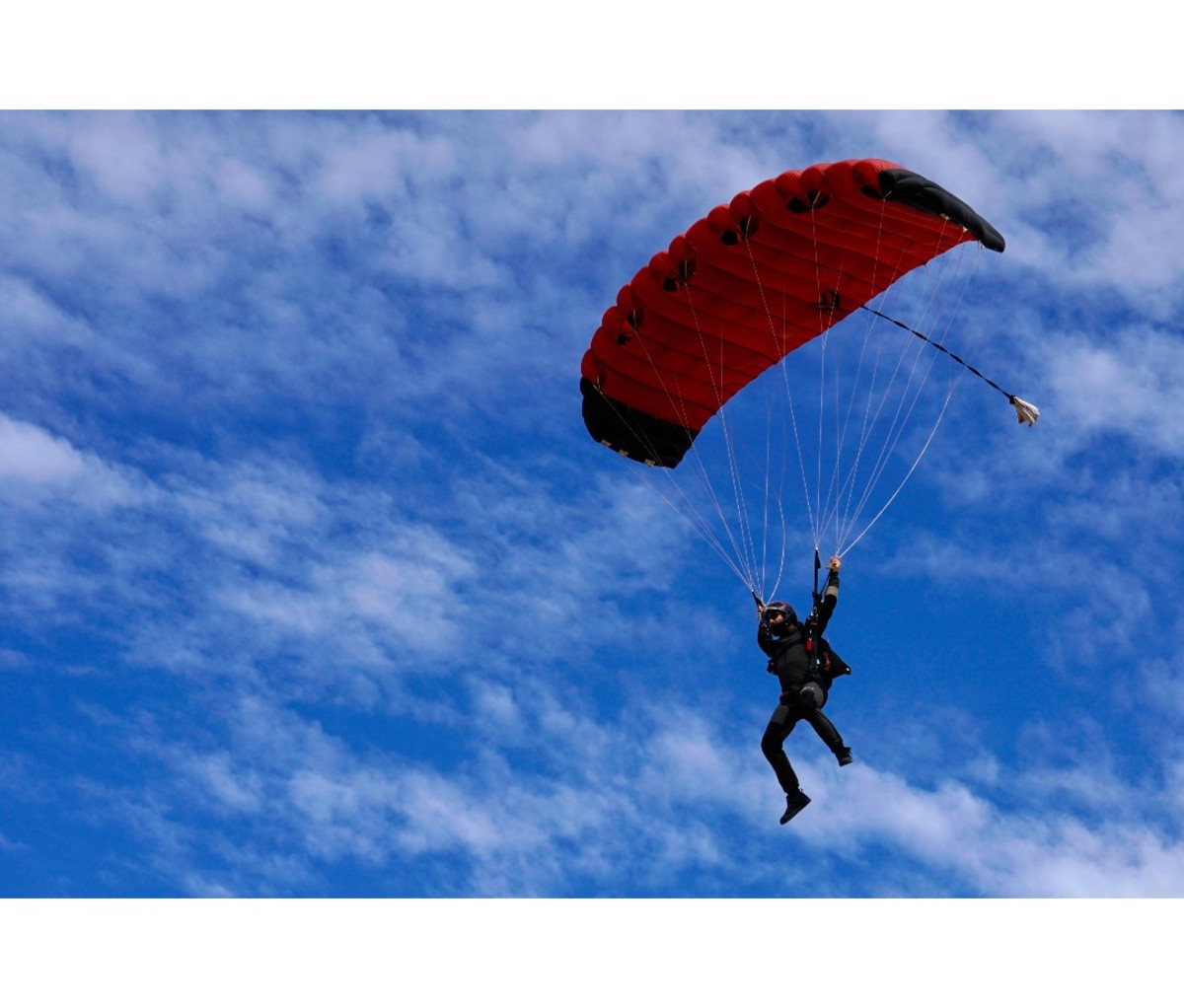 Skydiver floating down to earth with red parachute