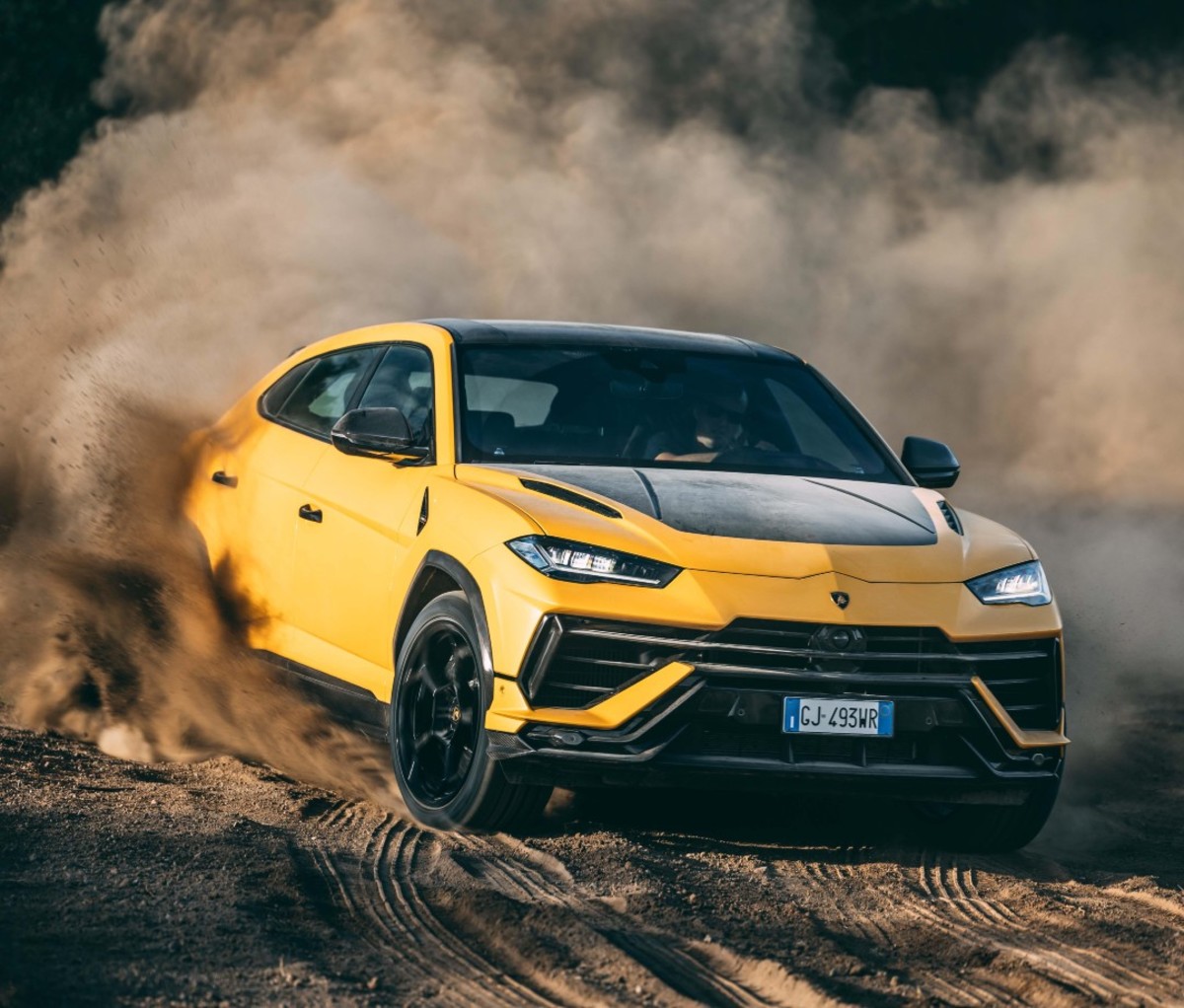 Yellow sport SUV riding through dirt, kicking up cloud of dust