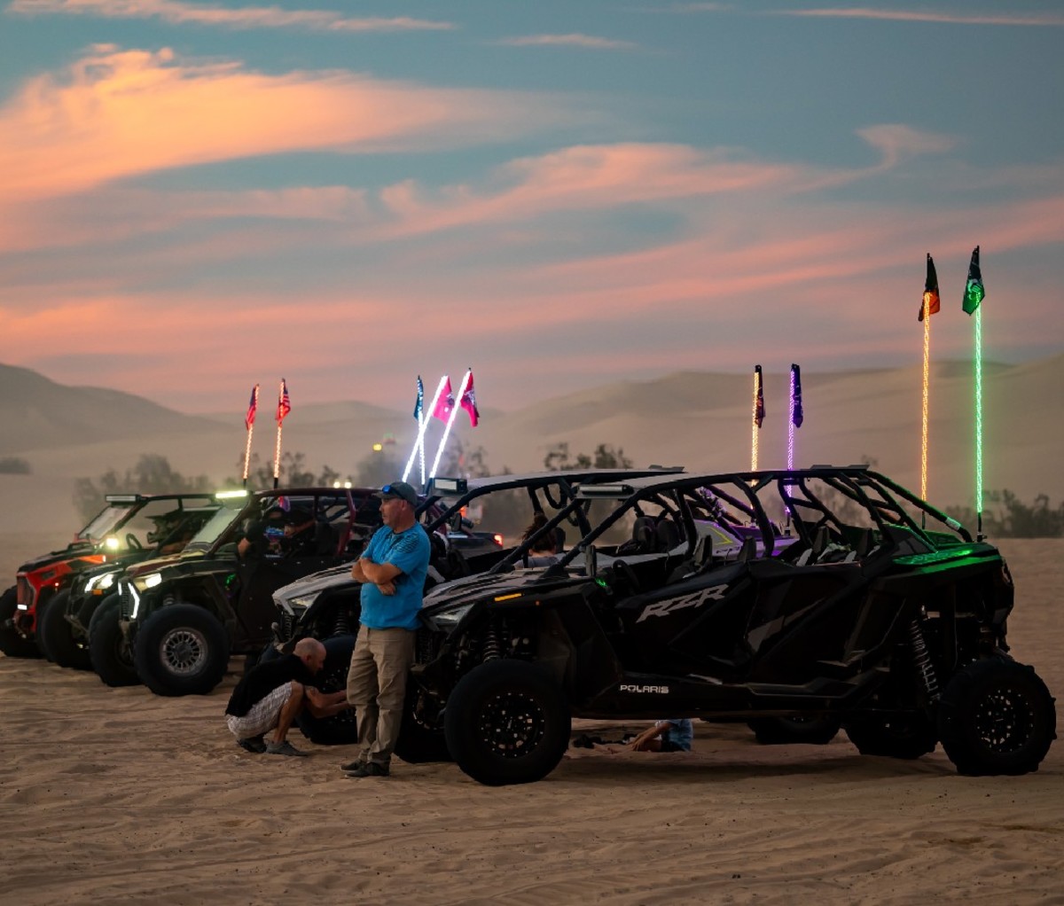 Off-riders at Camp RZR lining up in the sand at dusk.