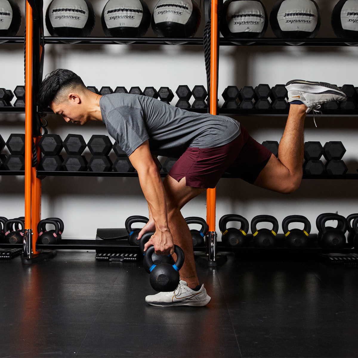 Athletic man wearing gray T-shirt and maroon shorts doing Single-leg Romanian Deadlift