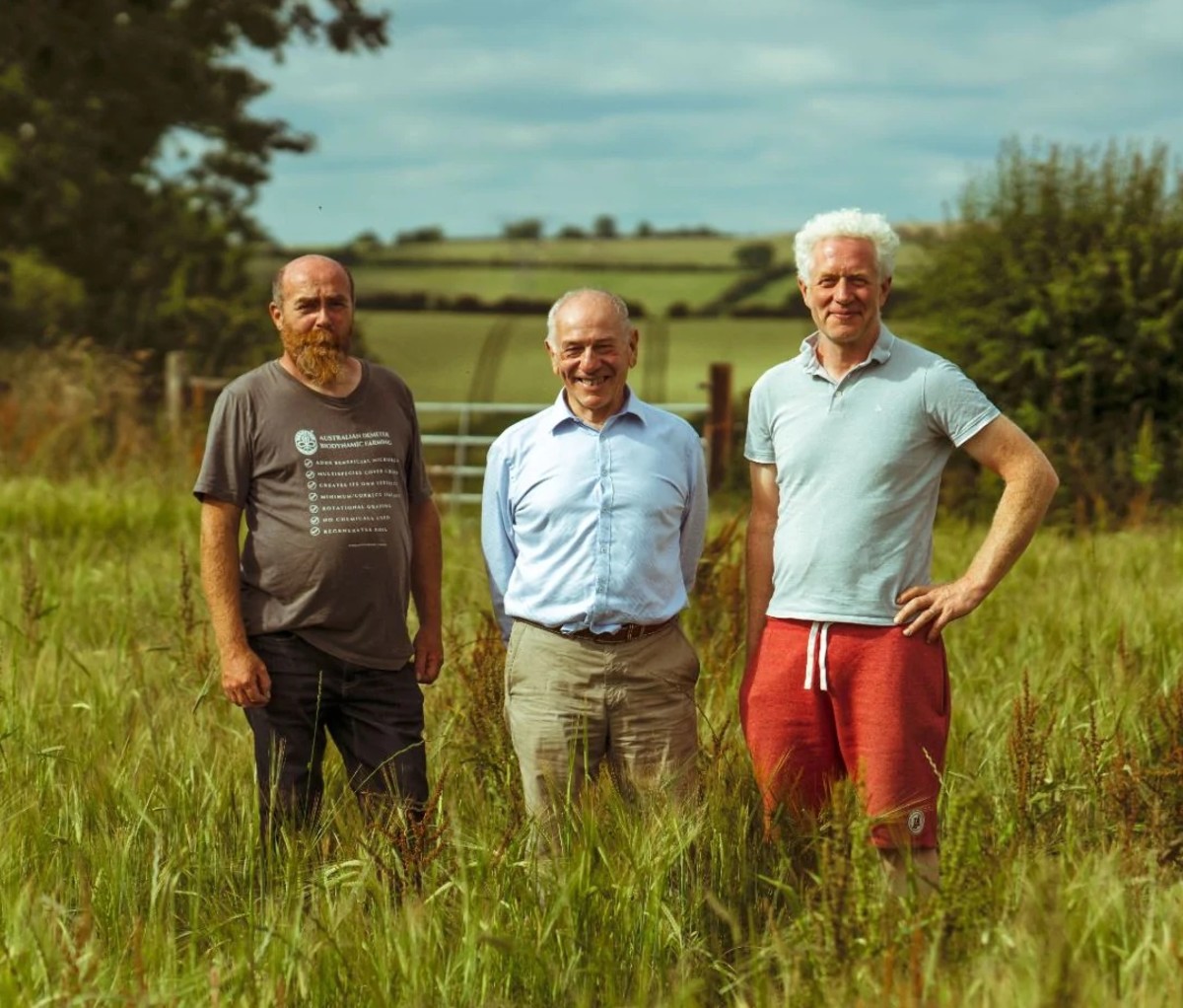 Three older caucasian men pose in field outside