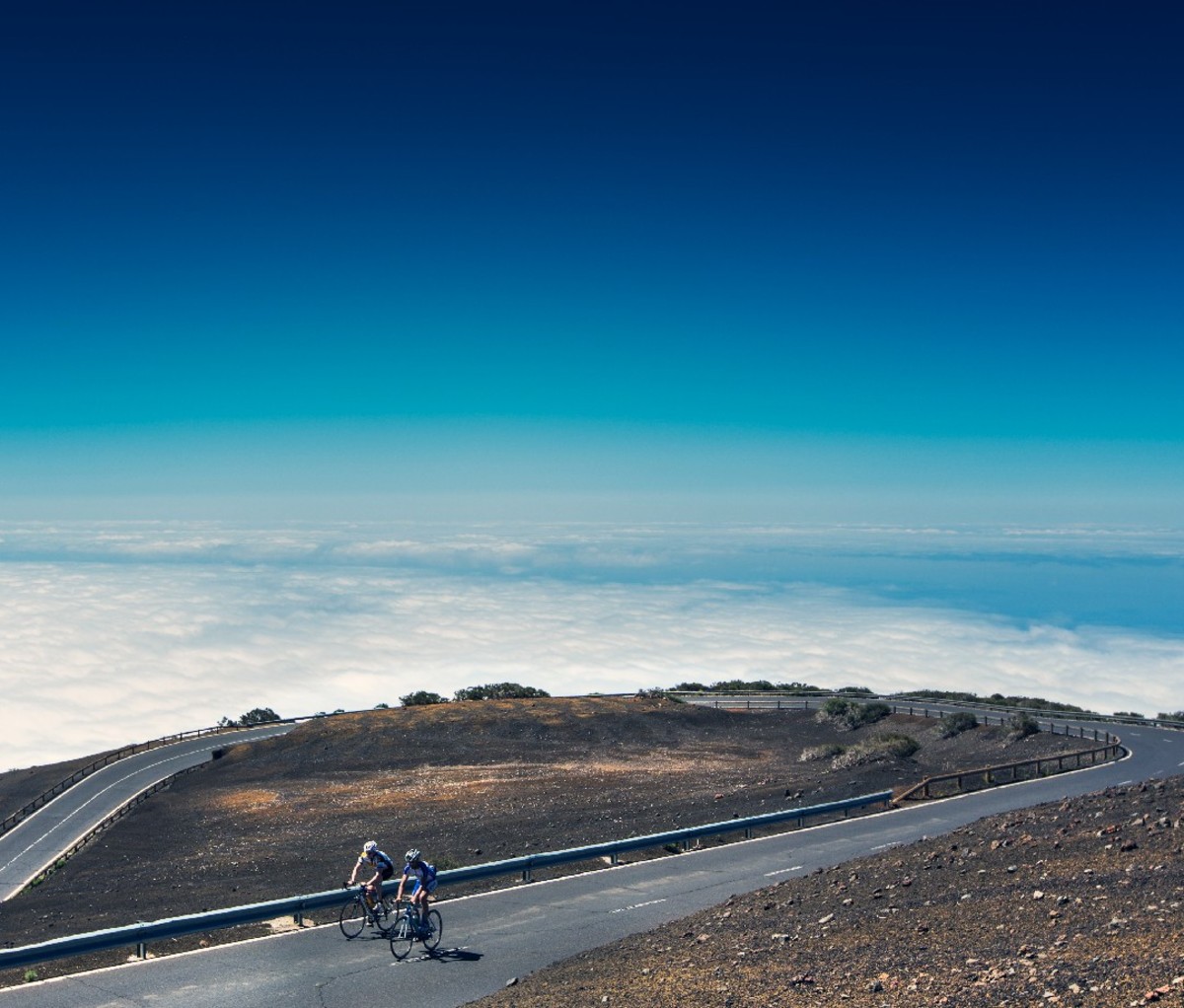 Couple biking on an empty highway above the clouds on Tenerife.