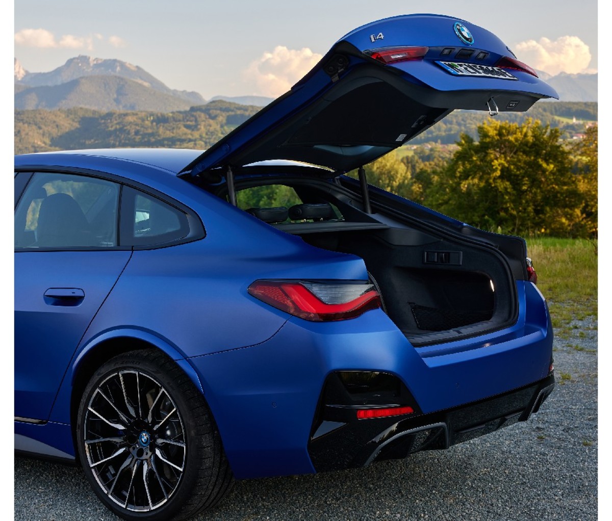 Blue BMW i4 M50 parked with trunk open. Rear view.