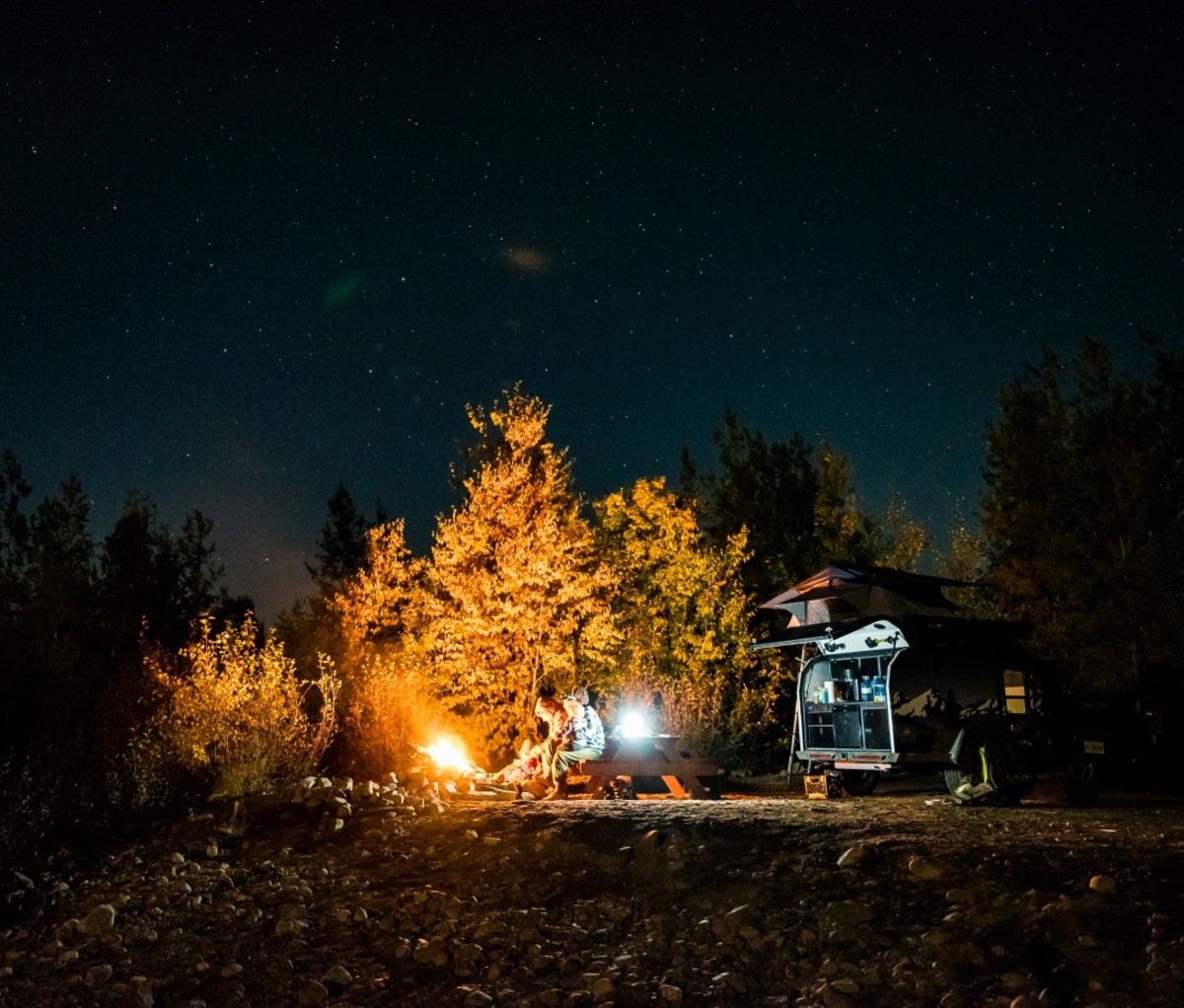 Nighttime view of a camper trailer and a fire at a campsite. Trans-Labrador Highway