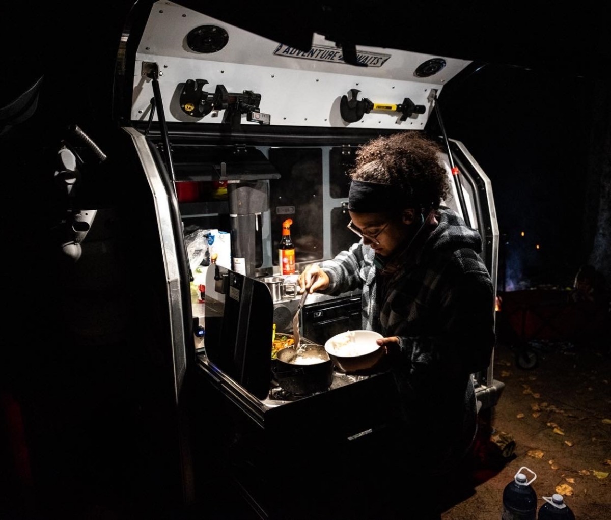 Cooking at night at a campsite beside a camper trailer. Trans-Labrador Highway