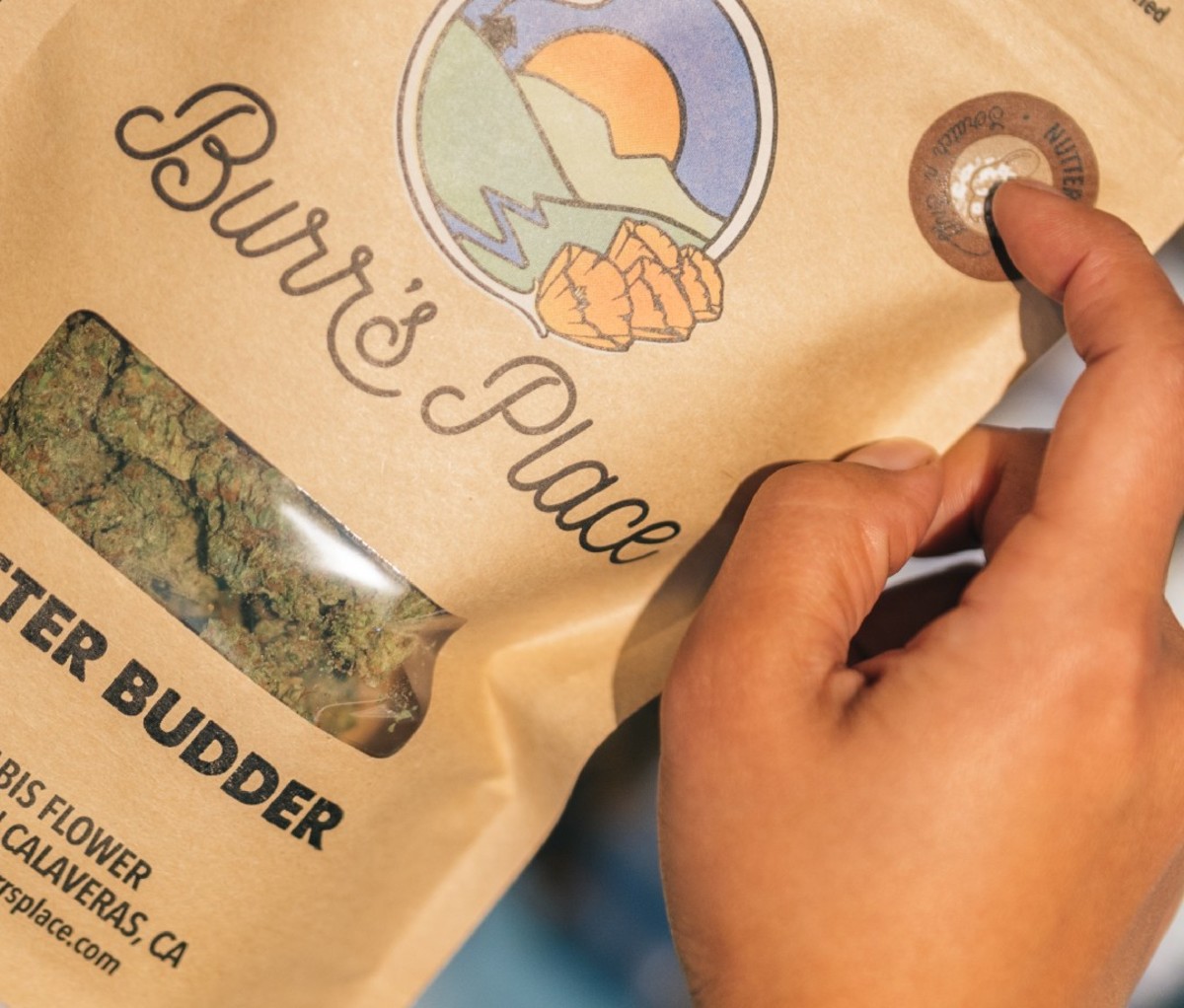 Finger scratching a "scratch and sniff" sticker on a bag of cannabis.