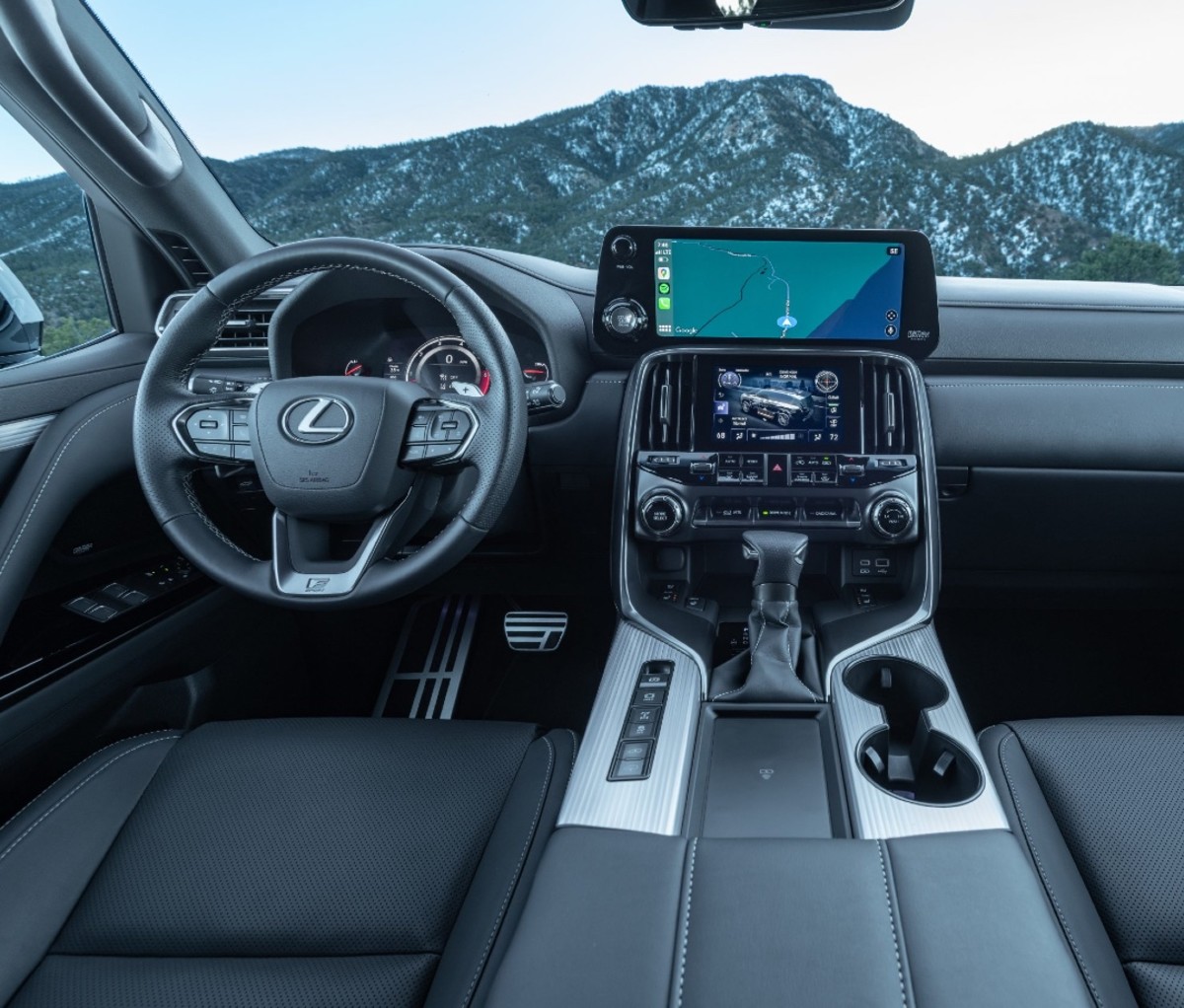 Silver and black leather interior of a luxury SUV with pine trees in the background.