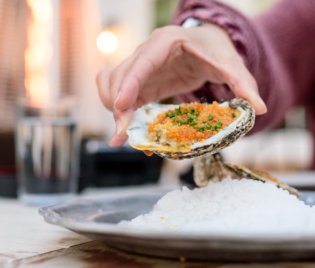 Caucasian man's hand holding roasted oyster