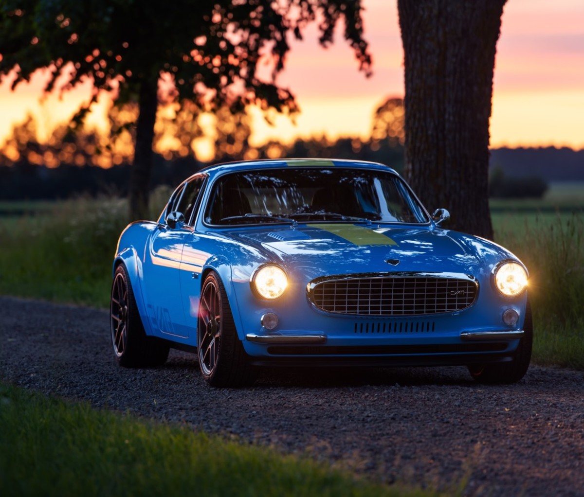 Blue restomod sports car parked outside at sunset