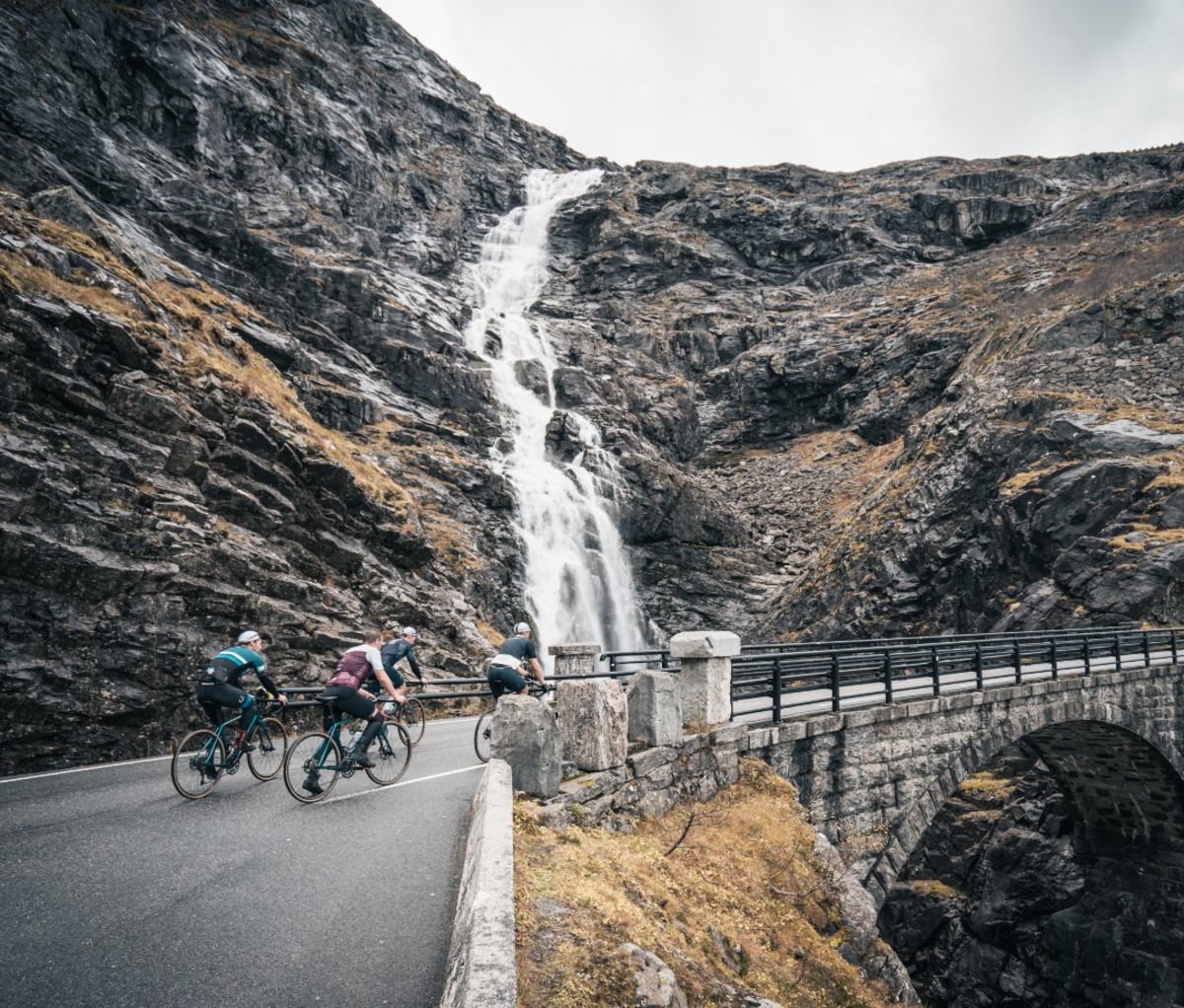 Cyclists riding over bridge by waterfall