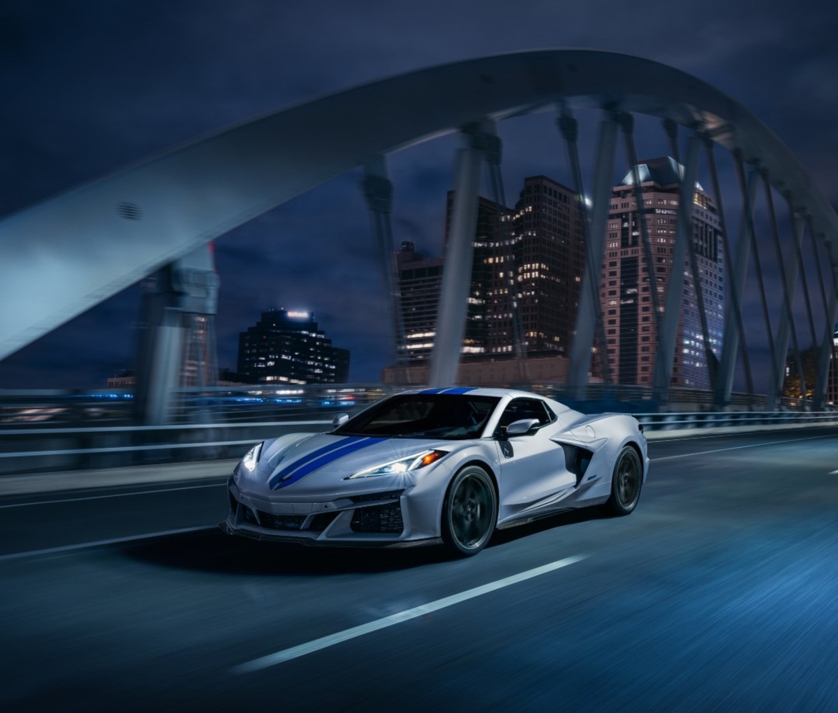 Gray sports car driving across bridge at night