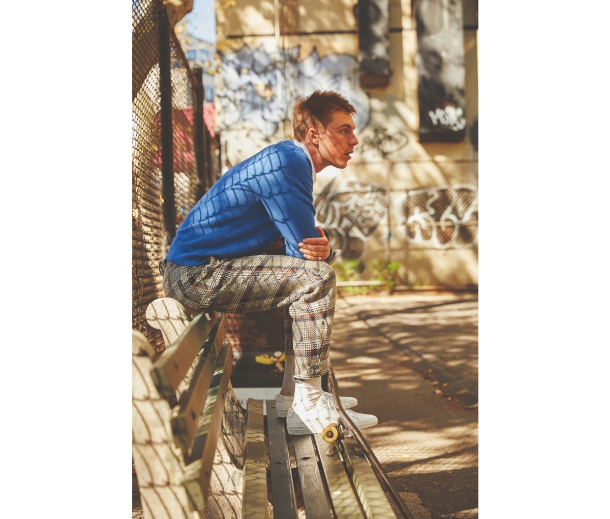 Man wearing a sweatshirt and sitting on a bench.