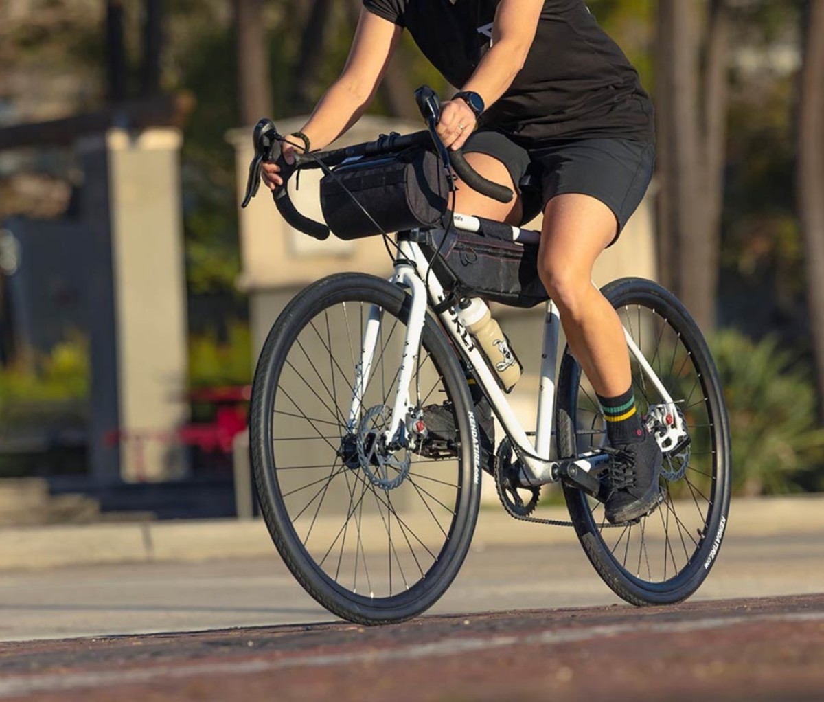 A person wearing black clothing riding a white Surly Preamble bike.