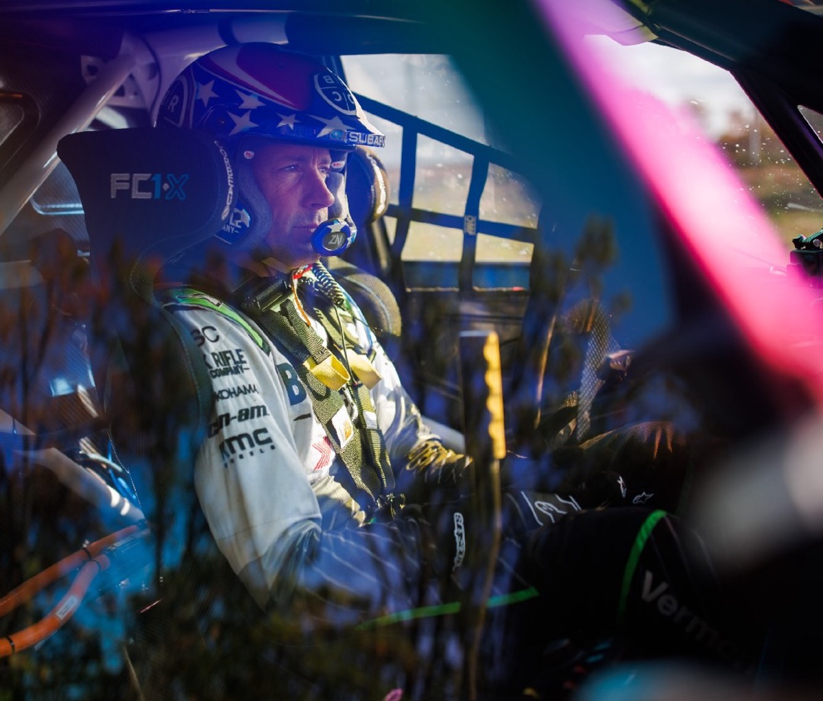 Race car driver sitting in a race car with a helmet on.