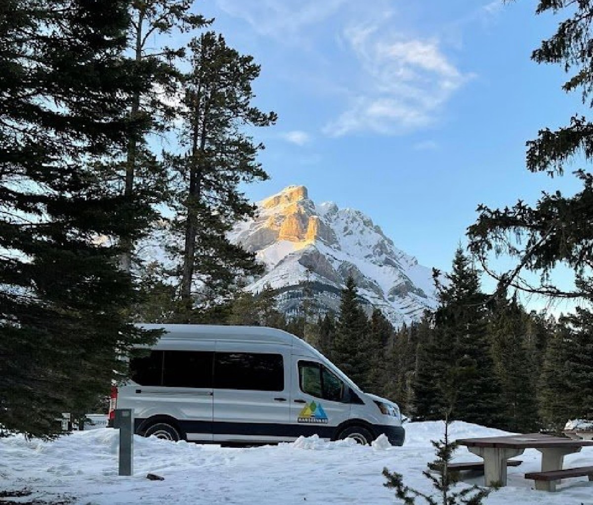 Camper van at a snowy campsite with a massive mountain in the background.